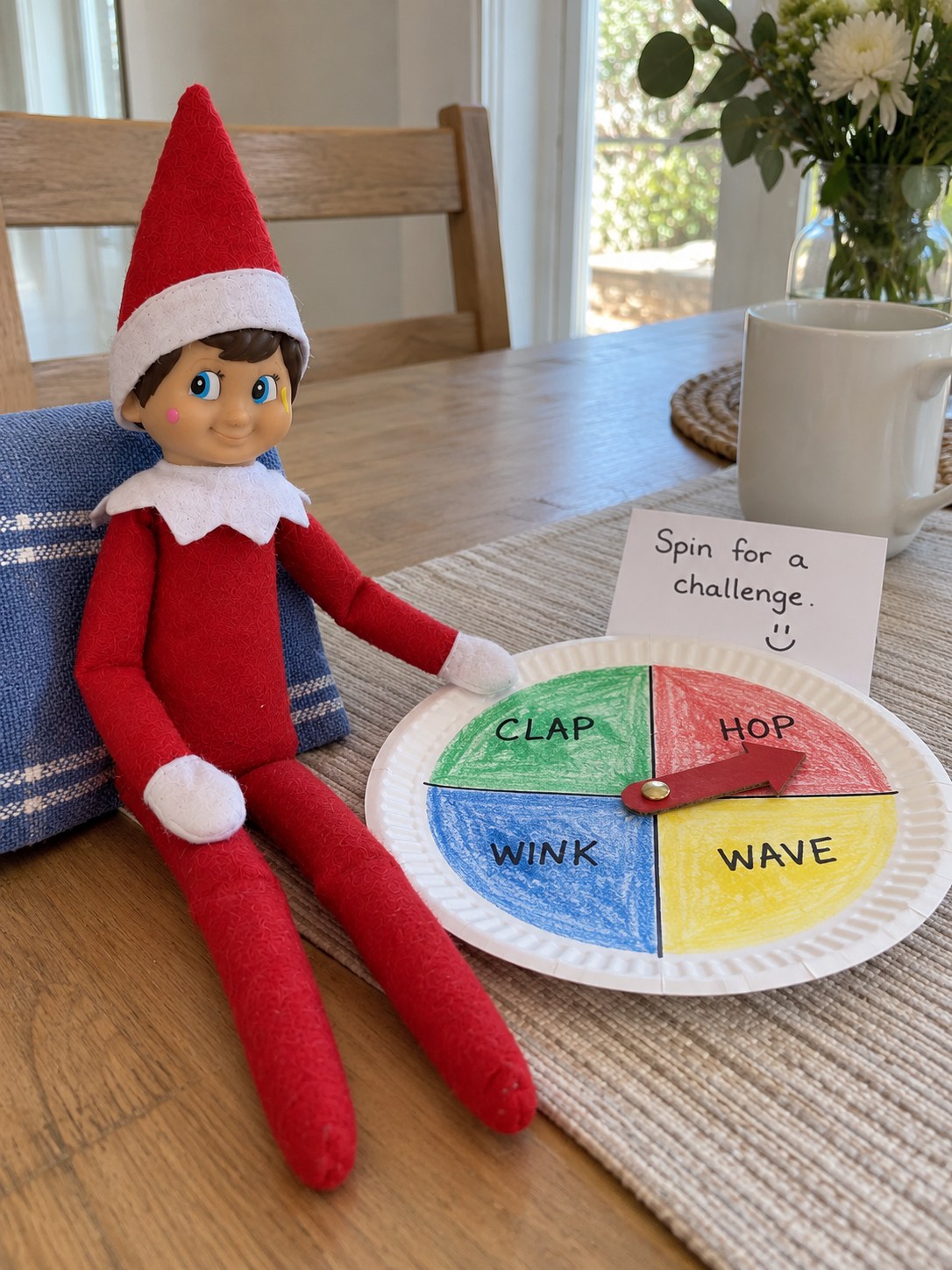 Tom’s elf beside a paper-plate spinner divided into Clap, Hop, Wave and Wink sectors, with a red arrow and a Spin for a challenge note.