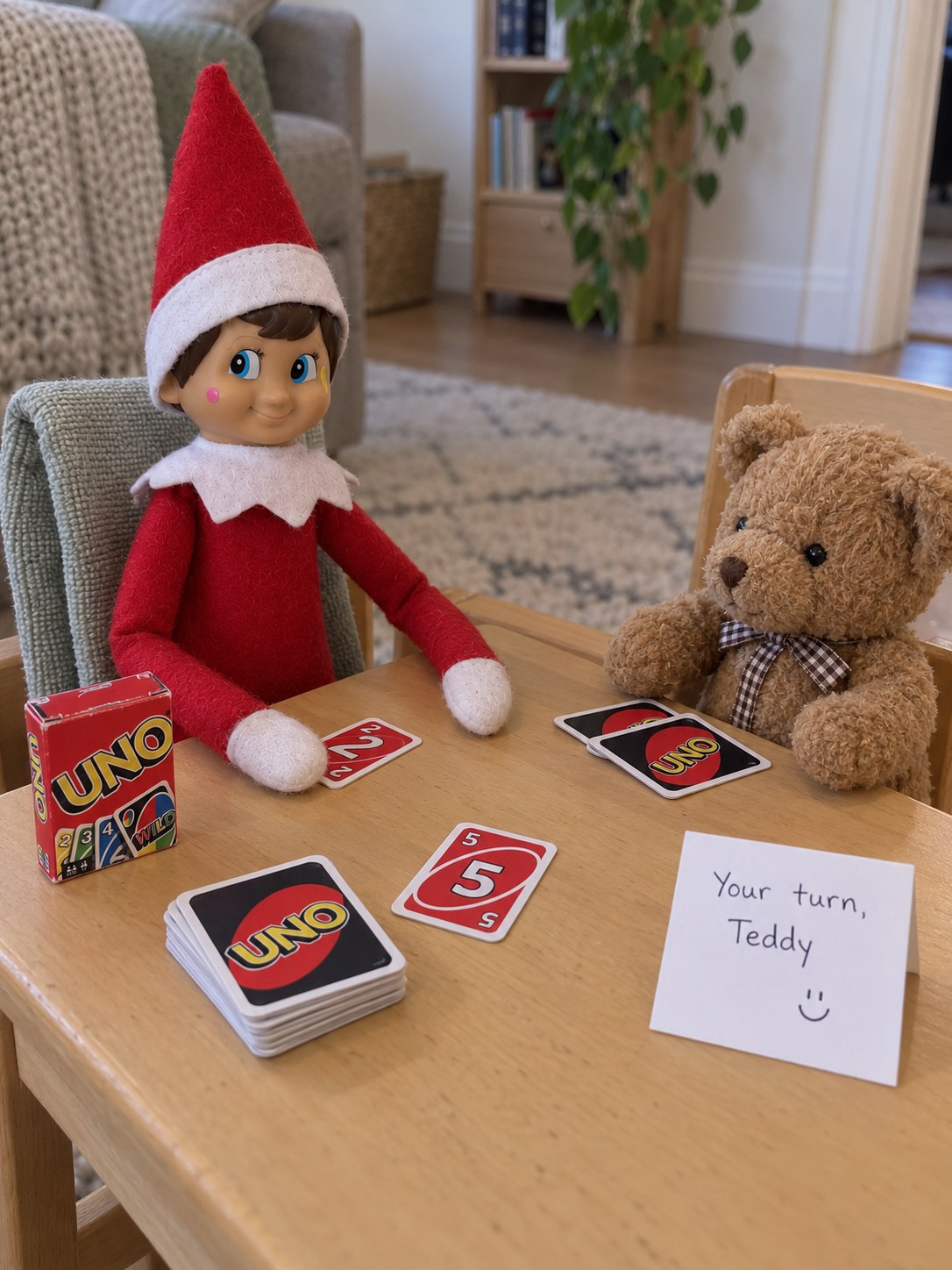 Tom’s elf and a teddy sitting opposite each other at a little table with miniature UNO cards and a Your turn, Teddy note.